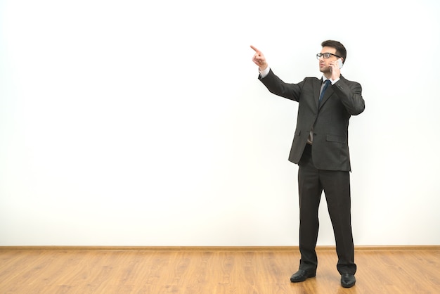 L'homme téléphone et fait des gestes sur le fond du mur blanc