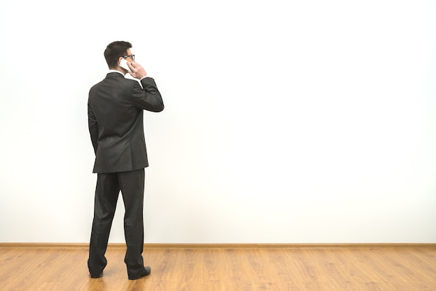 L'homme téléphone sur le fond du mur blanc