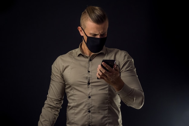 Homme avec un téléphone sur un mur noir