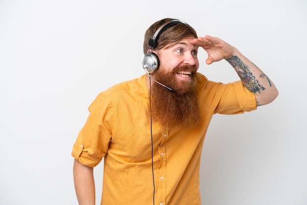 Homme de télévendeur isolé sur fond blanc regardant loin avec la main pour regarder quelque chose