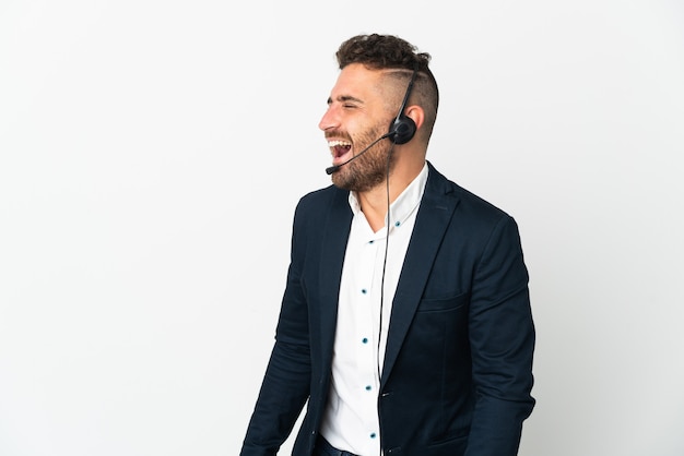 Homme de télévendeur travaillant avec un casque isolé sur fond blanc en riant en position latérale