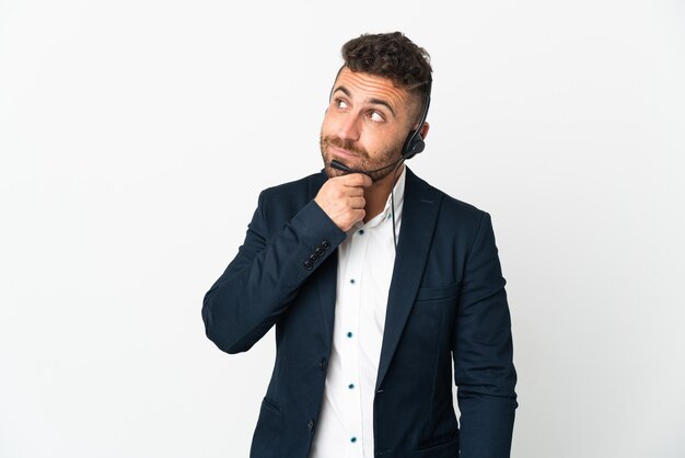 Homme de télévendeur travaillant avec un casque isolé sur un mur blanc et regardant vers le haut