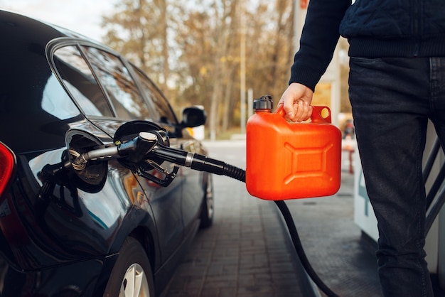 Homme tenant un bidon sur une station-service, remplissage de carburant. Ravitaillement en essence, service de ravitaillement en essence ou diesel, ravitaillement en pétrole