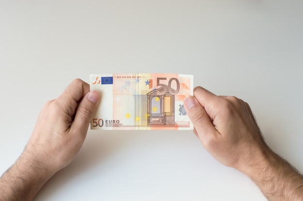 Homme tenant un billet de cinquante euros dans ses mains