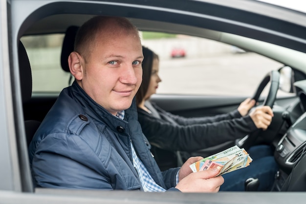 Homme tenant des billets en euros assis dans la voiture