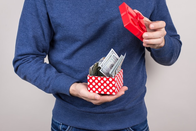 Homme tenant une boîte cadeau ouverte avec de l'argent