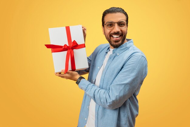 Un homme tenant une boîte à cadeaux vers la caméra