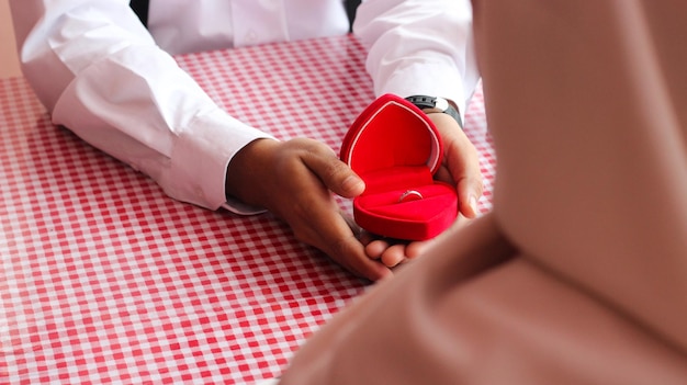 Photo l'homme tenant la boîte rouge en forme d'amour propose à sa petite amie