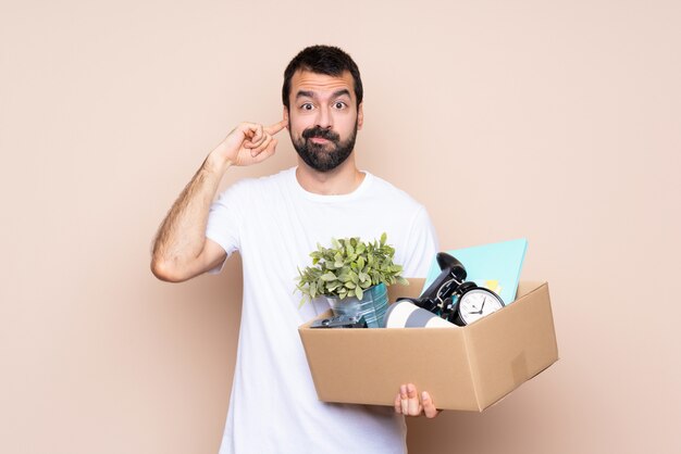 Homme tenant une boîte et se déplaçant dans une nouvelle maison sur un mur isolé frustré et couvrant les oreilles