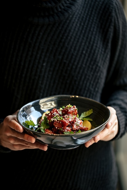 Homme tenant un bol de poulet mariné en sauce épicée avec daikon