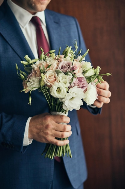 Homme tenant un bouquet de mariée dans les mains le marié se prépare le matin avant la cérémonie de mariage