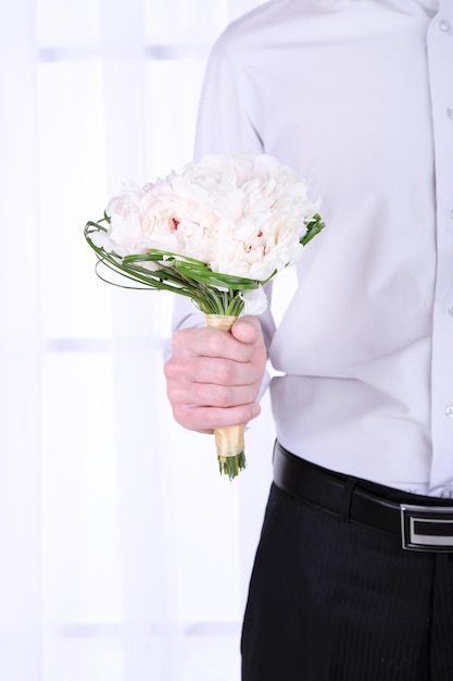 Homme tenant un bouquet de mariée sur fond clair