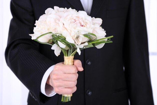 Homme tenant un bouquet de mariée sur fond clair