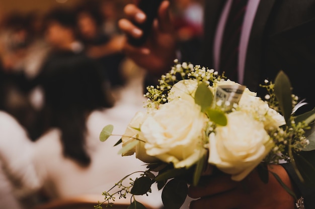 Un homme tenant un bouquet de roses blanches