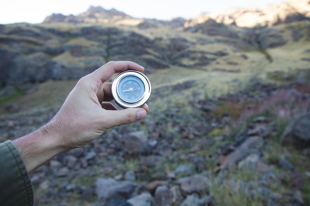 Homme tenant une boussole sur un fond de montagne