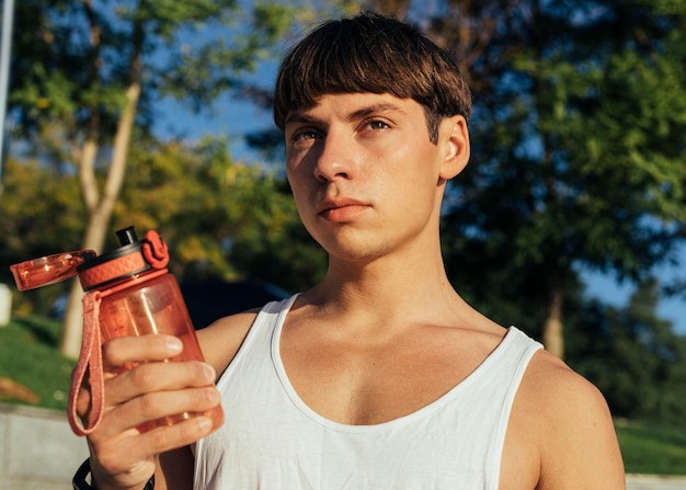 Photo homme tenant une bouteille d'eau à boire après avoir travaillé