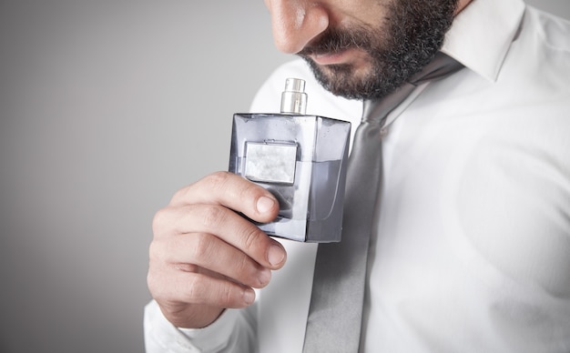 Homme tenant une bouteille de parfum.