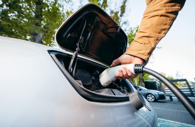 Homme tenant le câble d'alimentation à la station de charge de véhicule électrique Gros plan