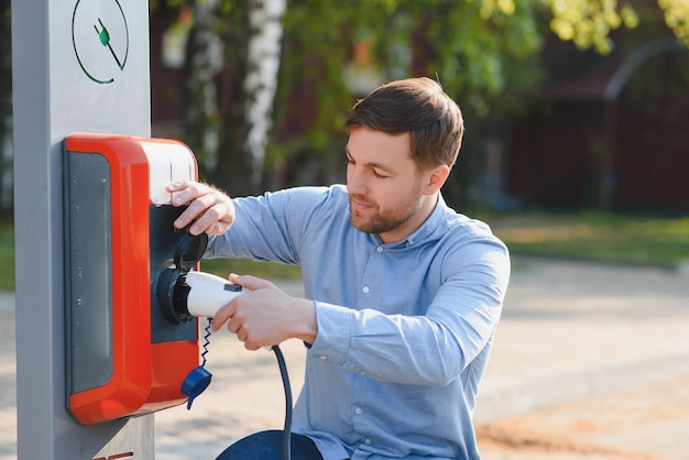 Homme tenant le câble de charge d'alimentation pour voiture électrique