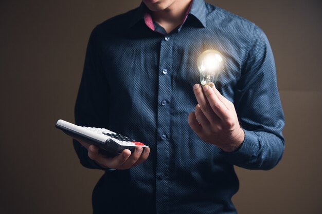 Homme tenant une calculatrice et une lampe sur une surface brune