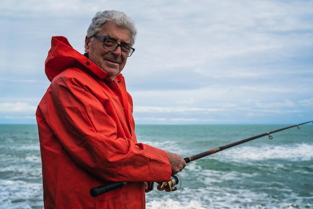 Un homme tenant une canne à pêche alors qu'il se tient au bord de la mer contre le ciel