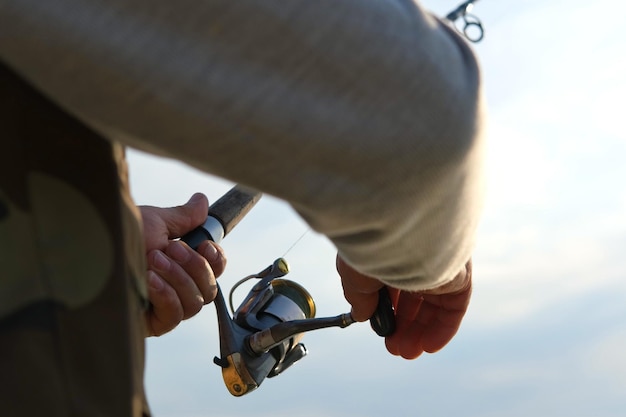 un homme tenant une canne à pêche avec un hameçon à la main.
