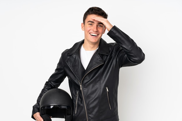 Homme tenant un casque de moto isolé sur mur blanc avec une expression faciale surprise