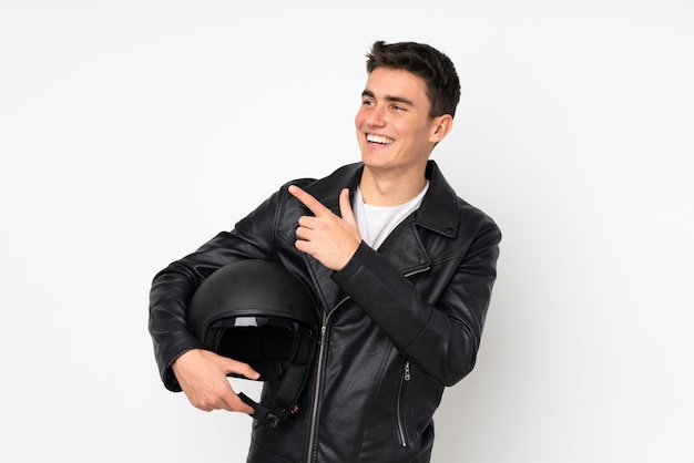 Homme tenant un casque de moto sur un mur blanc pointant avec l'index une excellente idée