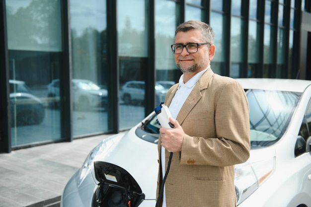 Homme tenant un connecteur d'alimentation pour voiture électrique