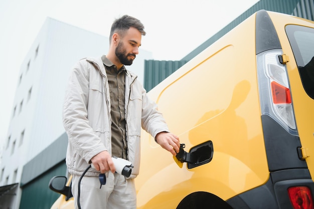 Homme tenant un connecteur d'alimentation pour voiture électrique