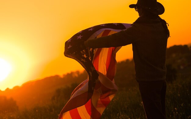 Photo homme tenant le drapeau américain au coucher du soleil