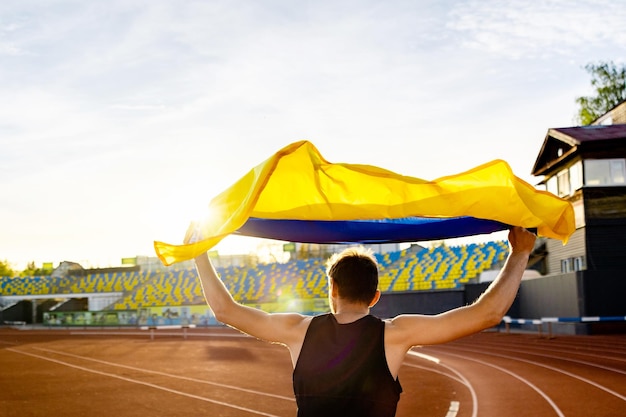 Un homme tenant un drapeau jaune devant un stade