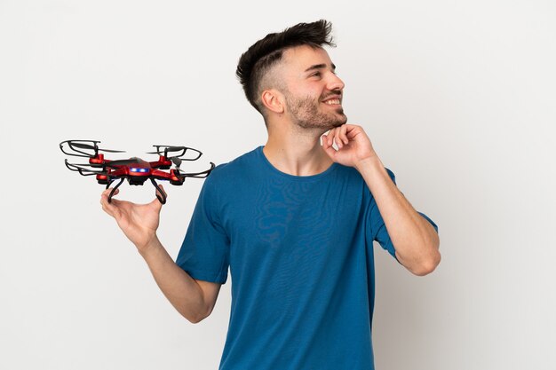 Homme tenant un drone isolé sur fond blanc pensant une idée tout en levant les yeux