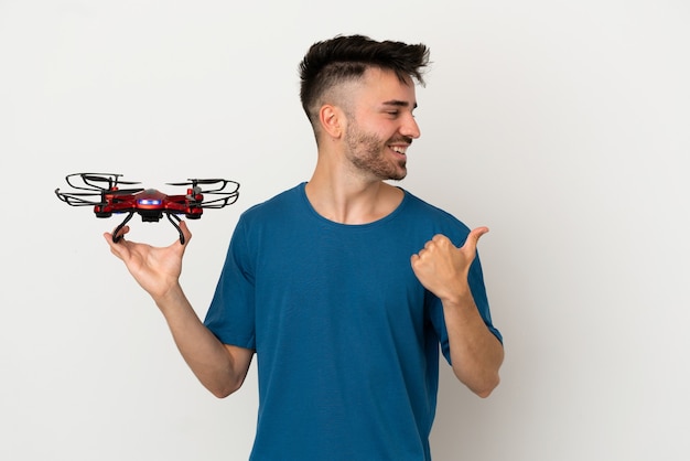 Homme tenant un drone isolé sur fond blanc pointant vers le côté pour présenter un produit