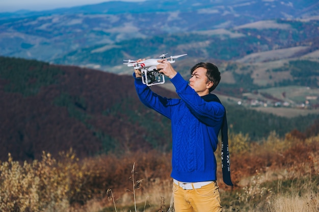 homme tenant un drone pour la photographie aérienne. silhouette contre le ciel du coucher du soleil