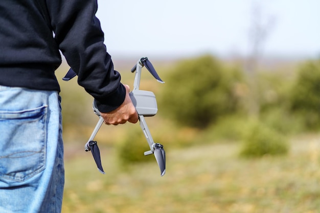 Homme tenant un drone avec sa main avant de le faire voler dans le ciel