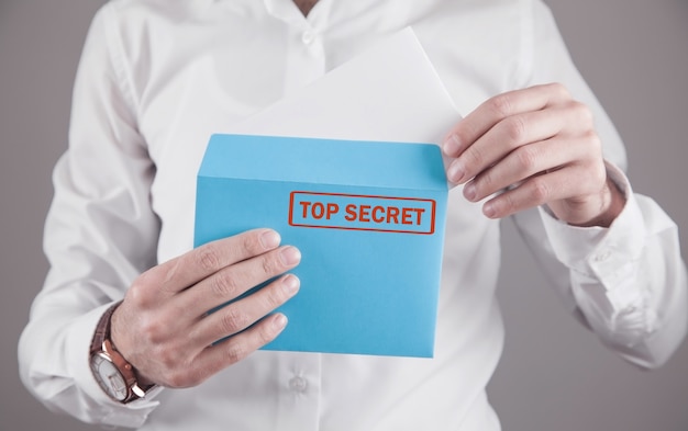 Homme tenant une enveloppe avec un cachet top secret.