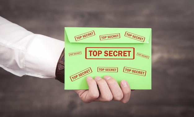Homme tenant une enveloppe avec un cachet top secret.