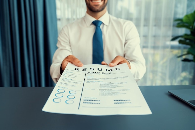 Un homme tenant un formulaire de CV devant une fenêtre.