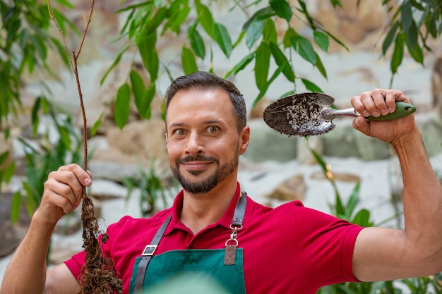 Homme tenant un jeune arbre et se prépare à planter dans le sol.