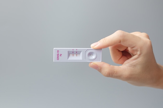 Homme tenant un kit de test d'antigène rapide avec un résultat positif lors du test d'écouvillonnage COVID-19. Test auto-nasal ou à domicile du coronavirus, concept de verrouillage et d'isolement à domicile