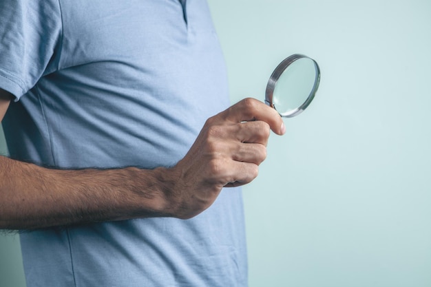 Homme tenant une loupe dans ses mains à la recherche d'informations