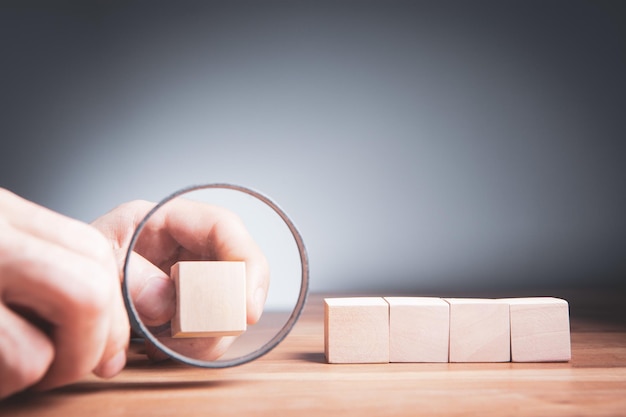 Homme tenant une loupe sous des cubes en bois