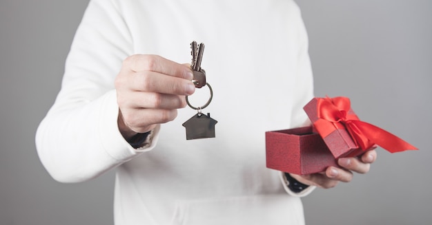 Homme tenant la maison et les clés avec boîte-cadeau.