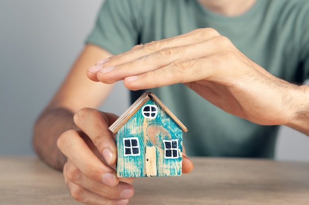 Un homme tenant une maison près de la table