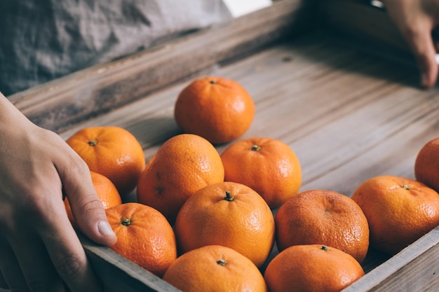 Un homme tenant des mandarines sur un plateau en bois