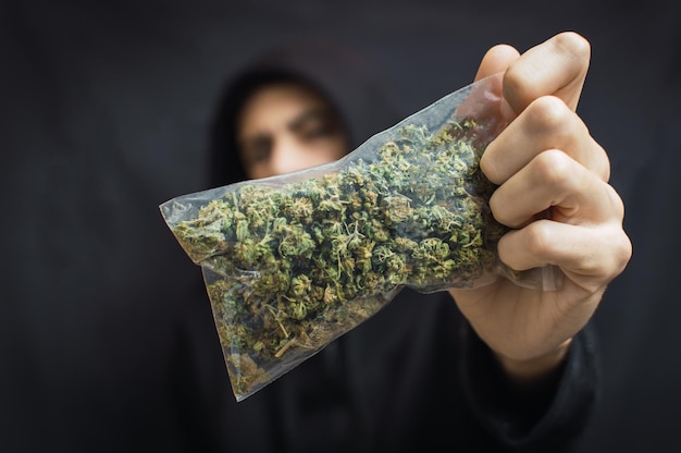 Un homme tenant de la marijuana sur un fond noir