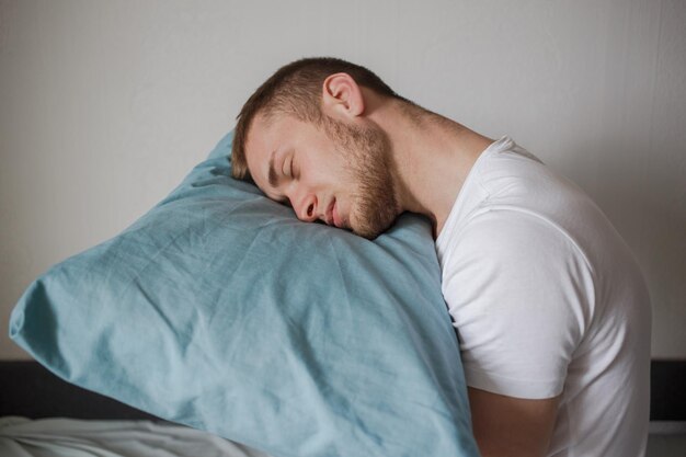 Un homme tenant un oreiller avec ses mains