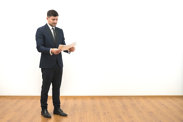 L'homme tenant des papiers sur le fond du mur blanc