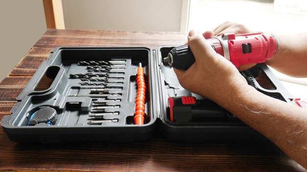 Homme tenant une perceuse à main électrique à la main avec un foret dans un coffret de bricolage